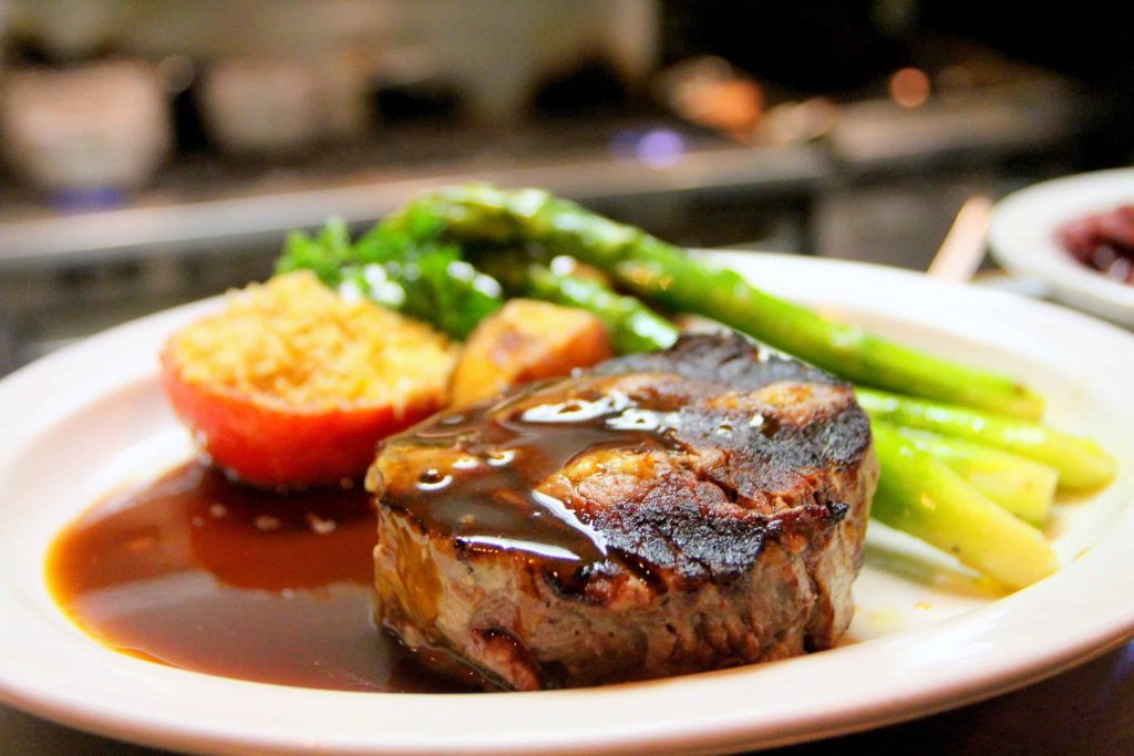 Xavier Steak with asparagus and cheese served on a white plate. 