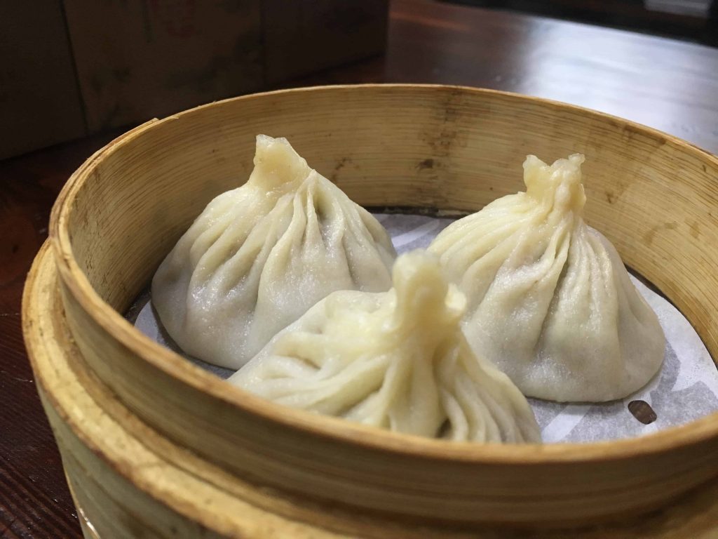3 dumplings served on a wooden plate, dumplings are one of the foods that start with D